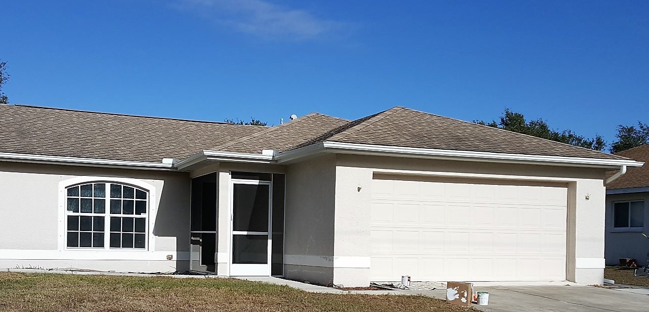 House front before painting, with bare stucco